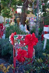 Festive outdoor Christmas display featuring decorative gift boxes wrapped with red bows in a garden setting in California, USA.