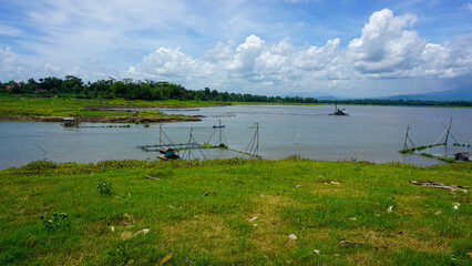Traditional fish farms on a large lake with mountains and cloudy sky background