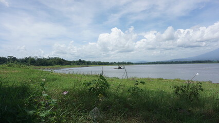 Traditional fish farms on a large lake with mountains and cloudy sky background