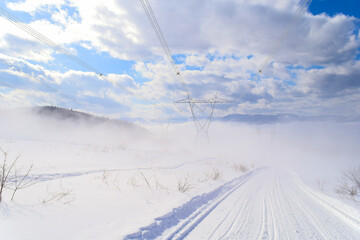 Snowmobile trail passing under high-voltage power lines in a mountainous region on a freezing winter day