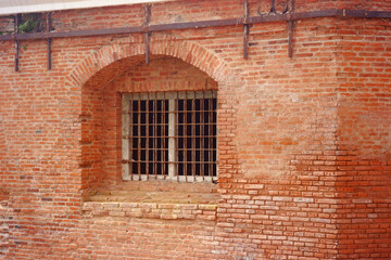 Prison windows with double iron bars and thick brick walls. Ancient prison, prison security.
