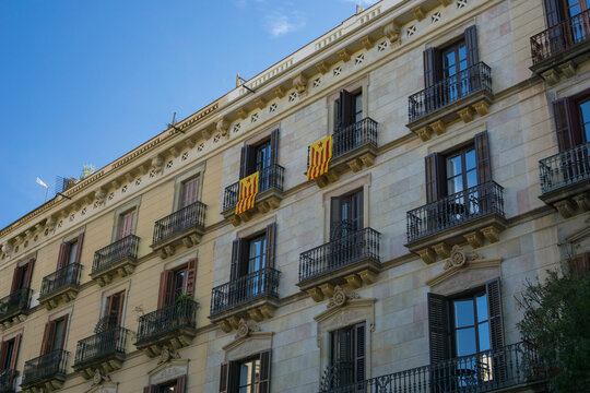 apartment building facade barcelona spain stone wall balconies historical residential architecture in gothic quarter or eixample with catalan flags hanging concept of real estate, tourism, lifestyle