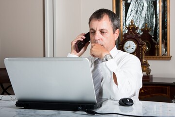 Businessman Working on Laptop While Talking on Phone