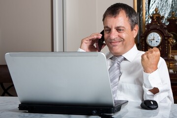 Businessman Working on Laptop While Talking on Phone