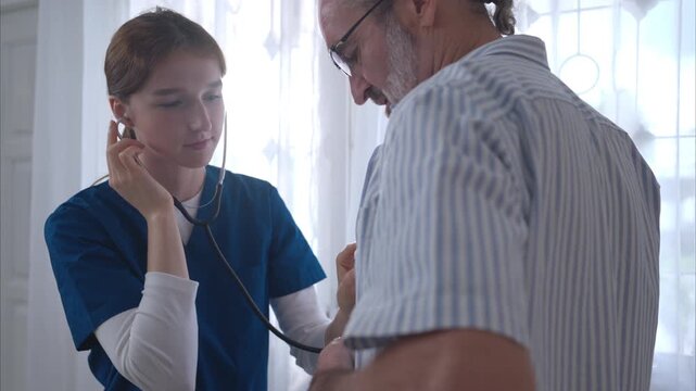 An elderly man and his doctor, standing by the window in the patient's room, talking and giving a preliminary examination