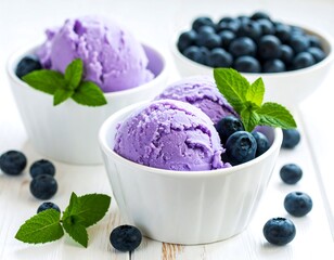 Purple ice cream scoops with mint and blueberries in white bowls, atop a white wooden table surface