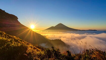 Mountain sunrise illuminates clouds below a volcanic peak, creating a serene, scenic landscape