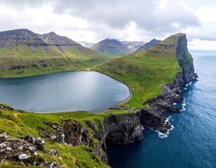 Lush green cliffs surround a still, dark bay under a cloudy sky, framed by jagged rocks in the foreground