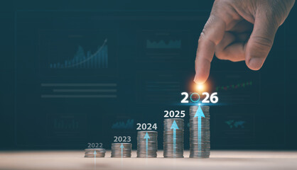 Financial growth concept. Stacked of coins rising by year from 2022 to 2026 and human finger touching the target. Investment planning, business success, profit growth, savings and economic forecast.