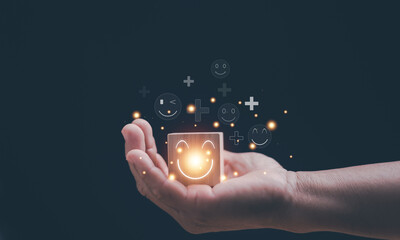 Customer satisfaction and positive experience concept. Glowing smile icon on wooden cube held in human hand and happy symbols. Service quality, emotional connection, brand trust and user happiness.