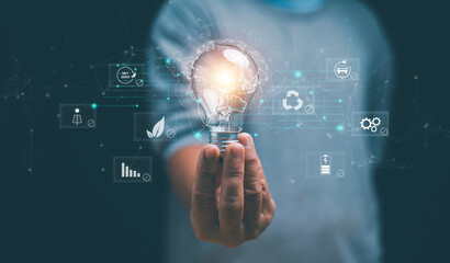 Sustainable innovation concept. Hand holding lightbulb with green energy and net zero icons. Clean technology, renewable energy, eco friendly business, carbon reduction and future sustainability.