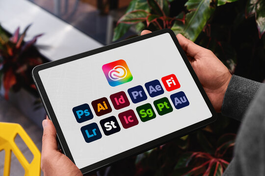 Person holding tablet displaying adobe creative cloud apps