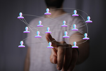 Concept of social network and global connections visualized. Hand pointing to linked network of avatars, representing digital networking.