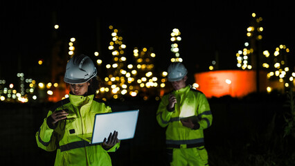 Energy professionals ensure 24 7 operations at a refinery. The team uses digital technology on a laptop to monitor sustainable production at night.