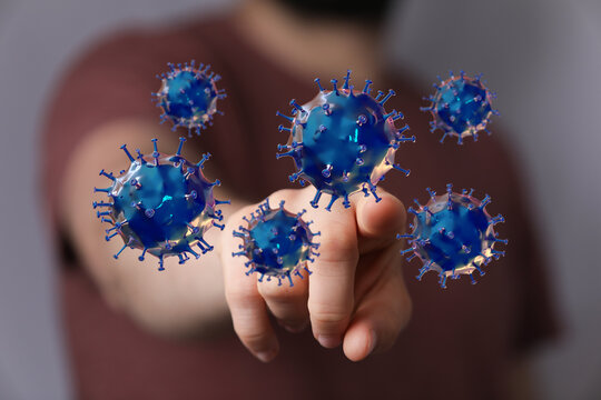 Concept image of a hand interacting with digital coronavirus models, representing disease, protection and figh
