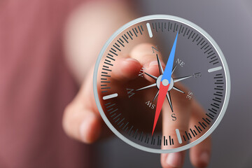 Fototapeta premium Hand holding a compass against a blurred background, suggesting direction, guidance, and navigation. Represents journey and planning.