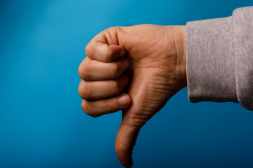 Image of a person's hand with the thumb pointing down, indicating disapproval or rejection. Set against a vibr