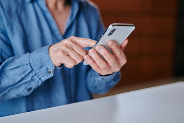 部屋でスマホを操作するシニア女性