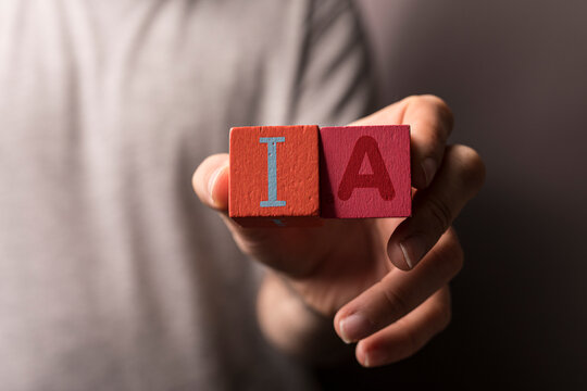 Close-up of a person's hand holding wooden blocks with the letters IA representing intelligence amplification