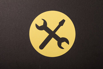 Abstract tools graphic of a wrench and screwdriver icon on a yellow circle set against a black textured backgrou