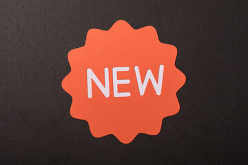An orange 'NEW' badge is displayed prominently against a dark textured background, ideal for concepts like sales