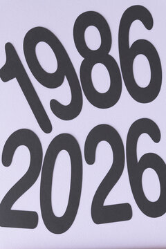 the years 1986 and 2026 machine-cut from black paper and arranged on textured paper