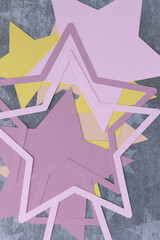 abstract background with machine-cut paper stars in pink and yellow