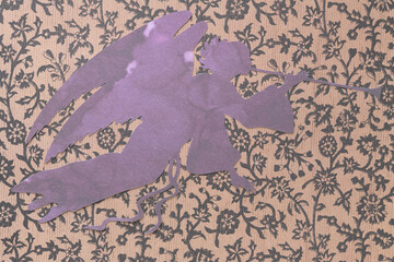 trumpeting angel machine-cut from marbled purple paper placed on decorative floral background