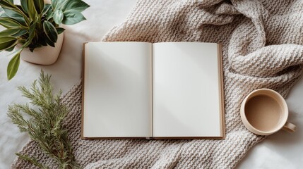 Open blank notebook next to a mug of coffee and green plants on a textured blanket