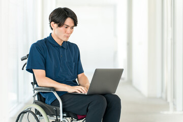 A young Asian man in a wheelchair using a computer (volunteer, fundraising, donation, charity,...