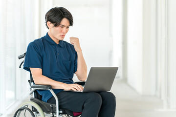 A young Asian man in a wheelchair using a computer (fist pump, hard work, success)