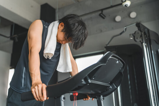 Young Asian man doing aerobic exercise on a walking machine in a sports gym