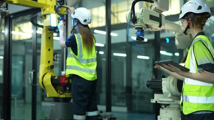 Collaborative engineering team calibrating smart industrial robotics. Female specialists using digital software to optimize automated manufacturing systems for future production efficiency. - Powered by Adobe
