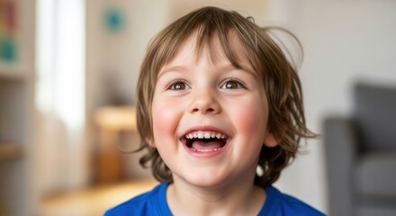A young boy with brown hair smiling and laughing in a living room.