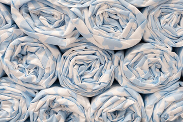 Stacked rolls of light blue and white patterned fabric. multiple rolls of soft fabric with blue and white patterns. Textile industry concept, laundry service.