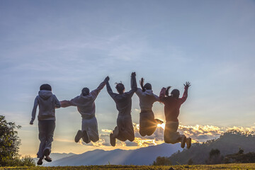 Groups of young friends happy jumping at the sunset on mountain to welcome the New Year.