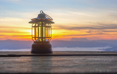 A lamp sits on a worn wooden floor at sunset over mountains