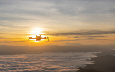Silhouette a drone flying over nature and making beautiful sunrise cloudy sky pictures and videos.