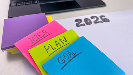 A close-up of colored sticky notes with the words plan, idea, and goal on a sheet of paper with the...