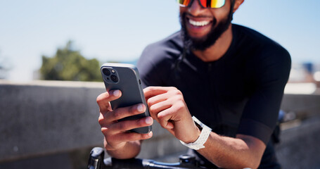 Hands, bicycle and phone for fitness in city, contact and smart watch with texting, break or tracking. Black man, bike and smartphone with mobile app, monitor and sky with exercise on bridge in town