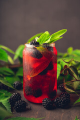 Blackberry sage cocktail with fresh branches on rustic wood. Selective focus.