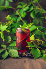Blackberry sage cocktail with fresh branches on rustic wood. Selective focus.