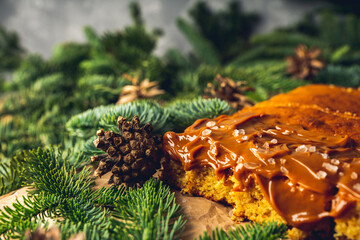 Salted caramel cake with fir branches on parchment paper. Selective focus.