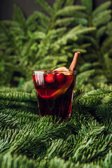 Mulled wine with orange, cranberry and cinnamon in fir forest setting. Selective focus.