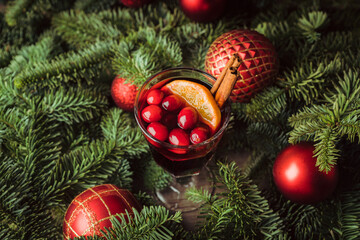 Mulled wine with orange, cranberry and cinnamon in fir forest setting. Selective focus.