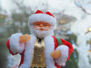Santa Claus toy close-up on the background of a blurred Christmas tree