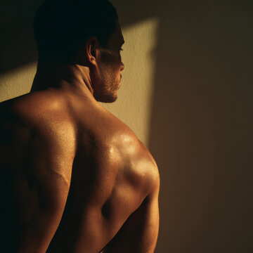 Close-up of a Black male torso and neck, sculpted by light and shadow, exploring human body, identity, and strength.