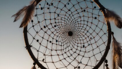 Dreamcatcher close-up with feathers against a soft blue sky.