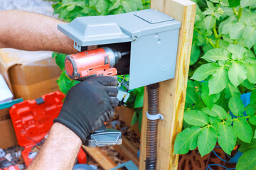 Worker operates power drill during installation at home garden