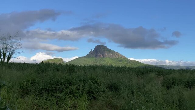 Scenic Landscape of Rempart Mountain with Lush Green Fields and Cloudy Blue Sky in Mauritius